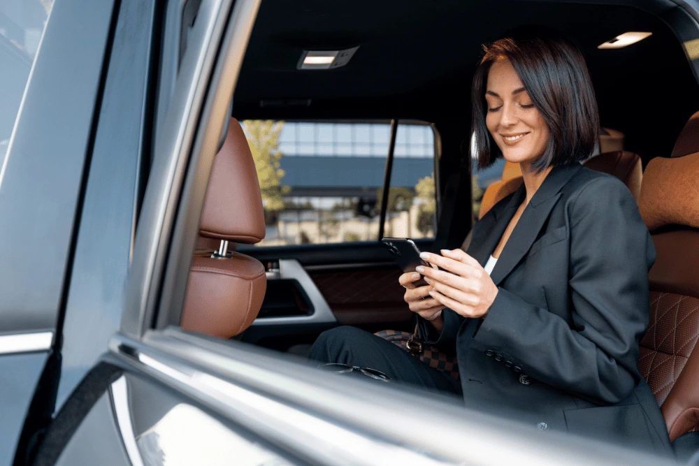 Mujer empresaria revisando su celular en auto alquilado